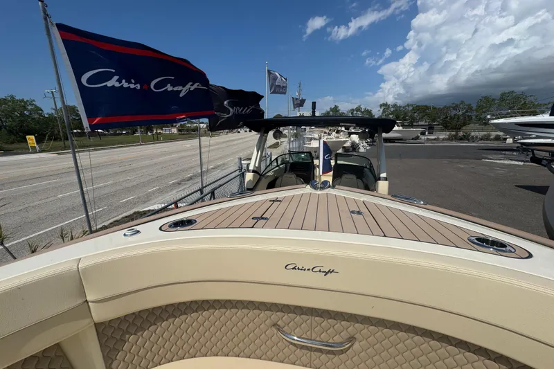 Slide: The Image of 2026 Chris-Craft Calypso 32 boat with flags, showcased outdoors under a partly cloudy sky. - 6