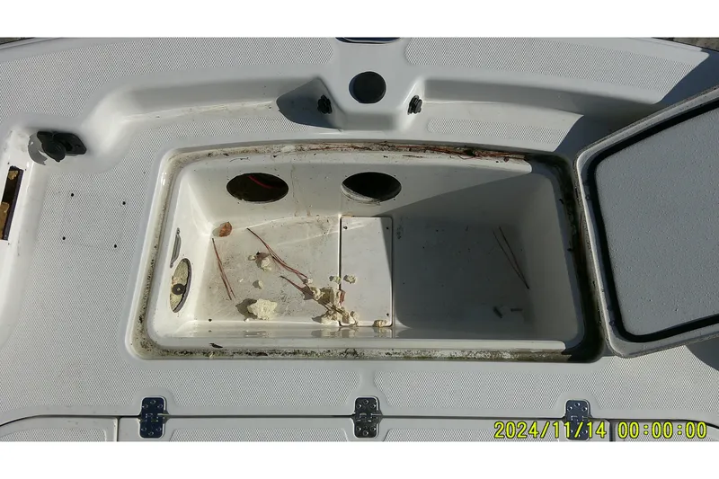 Slide: The Image of Open storage compartment on 2024 Mako Pro Skiff 19 CC boat, showing debris inside. - 10