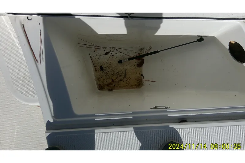 Slide: The Image of Open storage compartment of 2024 Mako Pro Skiff 19 CC boat, showing debris inside. - 12