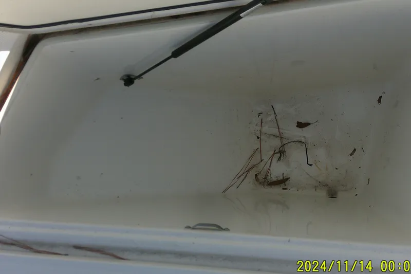 Slide: The Image of Open storage compartment of 2024 Mako Pro Skiff 19 CC boat, showing debris inside. - 14