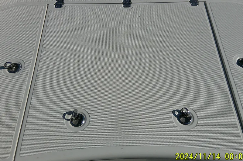 Slide: The Image of 2024 Mako Pro Skiff 19 CC deck with metal latches, textured surface. - 15