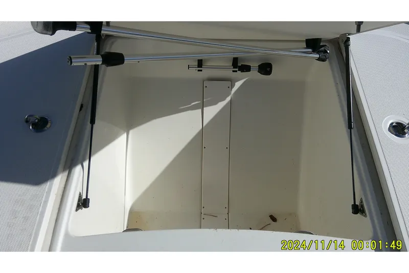 Slide: The Image of 2024 Mako Pro Skiff 19 CC storage compartment with hydraulic struts and clean interior. - 16