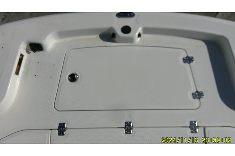 Slide: The Image of 2024 Mako Pro Skiff 19 CC boat deck with storage compartment and hinges. - 9