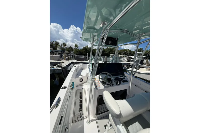 Slide: The Image of 2024 TwinVee 240 CFX CC boat interior with steering console and seating, docked under a clear sky. - 4