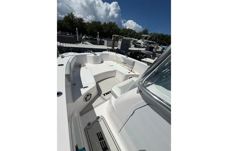 Slide: The Image of 2024 TwinVee 240 CFX CC boat interior with seating and storage, docked under a clear sky. - 5