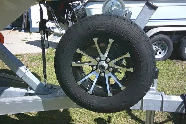 Slide: The Image of Trailer wheel for 2024 Carolina Skiff 21 LS boat on grass. - 3