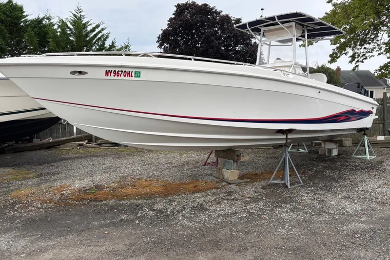 The Image of 1999 Wellcraft 302 Scarab Sport boat on stands, white hull with red and blue accents. - 0