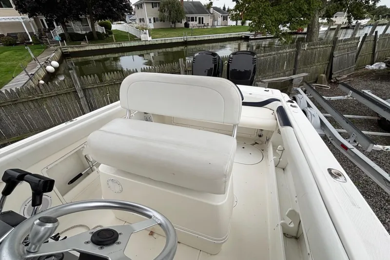 Slide: The Image of 1999 Wellcraft 302 Scarab Sport boat interior with steering wheel and seating, docked by a canal. - 6