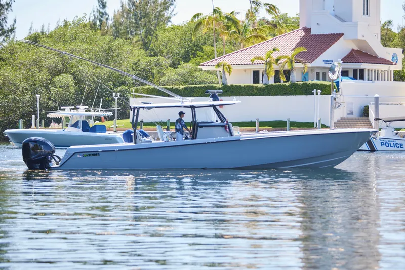 Slide: The Image of 2022 Contender 44 ST boat on calm water near a marina with lush greenery. - 10