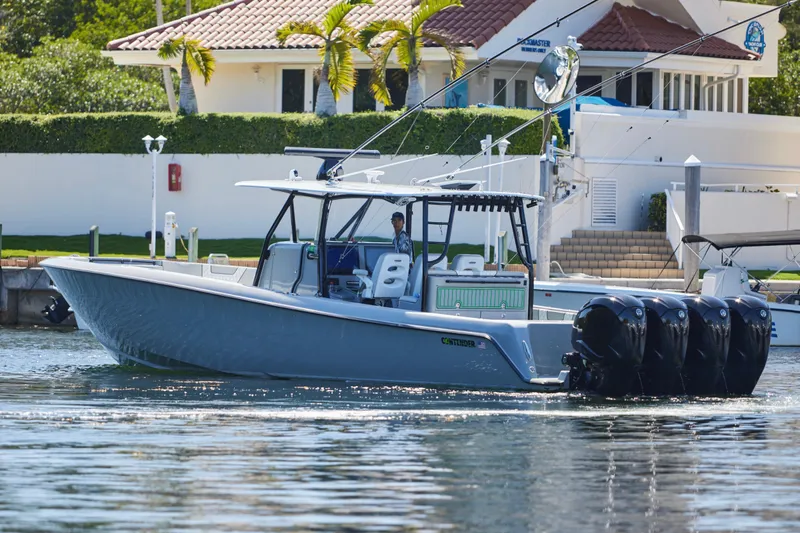 Slide: The Image of 2022 Contender 44 ST boat with four engines cruising near a waterfront home. - 12