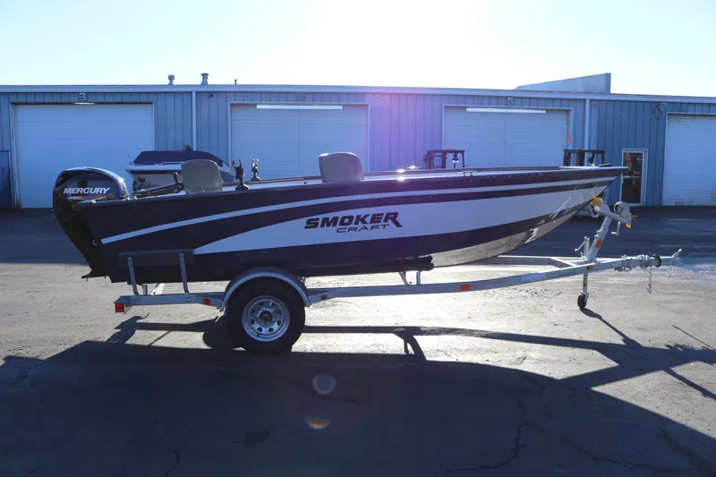 The Image of 2026 Smoker Craft Pro Lodge 160 boat on trailer, parked outside industrial building. - 0