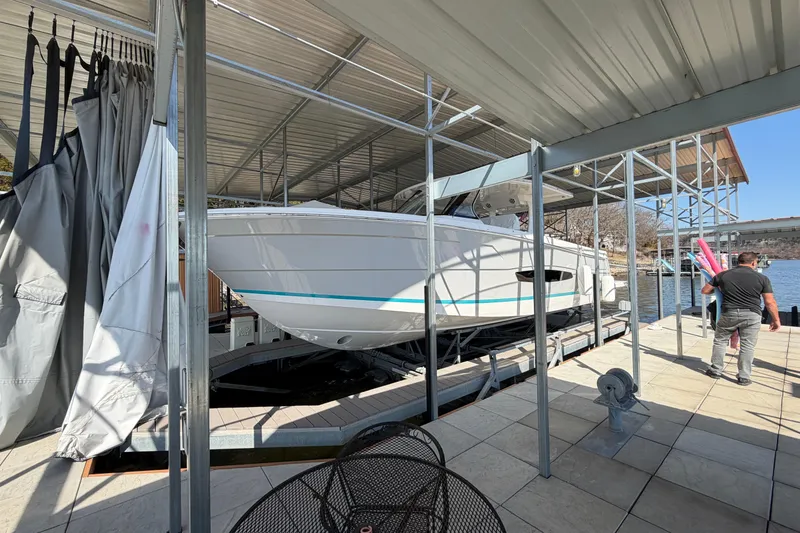 Slide: The Image of 2023 Regal 38 SAV boat interior with seating and table, docked by a scenic lake. - 26