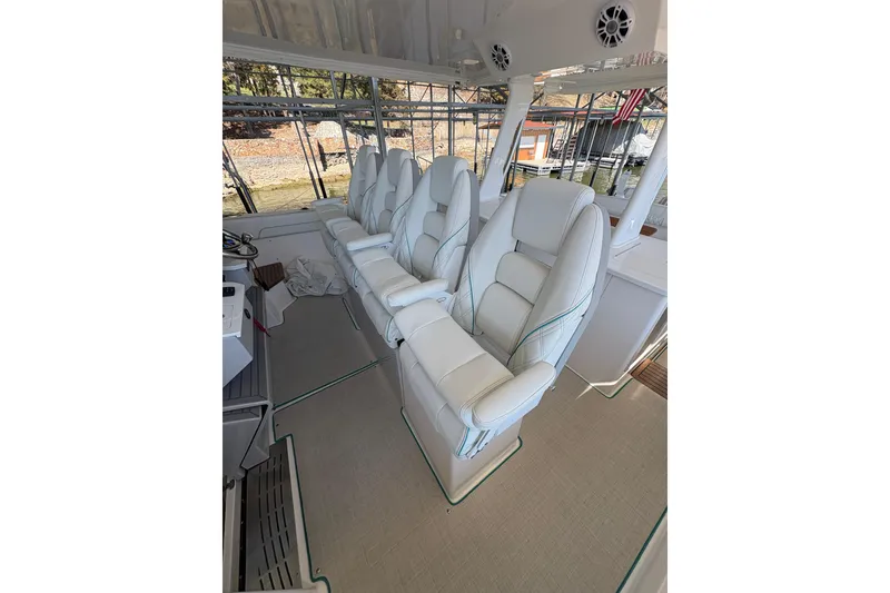 Slide: The Image of 2023 Regal 38 SAV boat interior with seating and table, docked by a serene lake. - 46