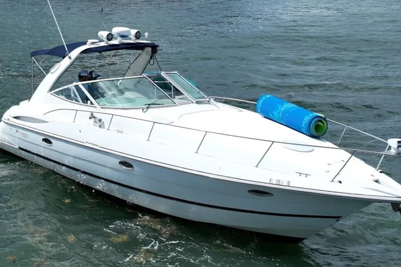 The Image of 2001 Cruisers Yachts 3470 Express boat cruising on water with blue mat on deck. - 1