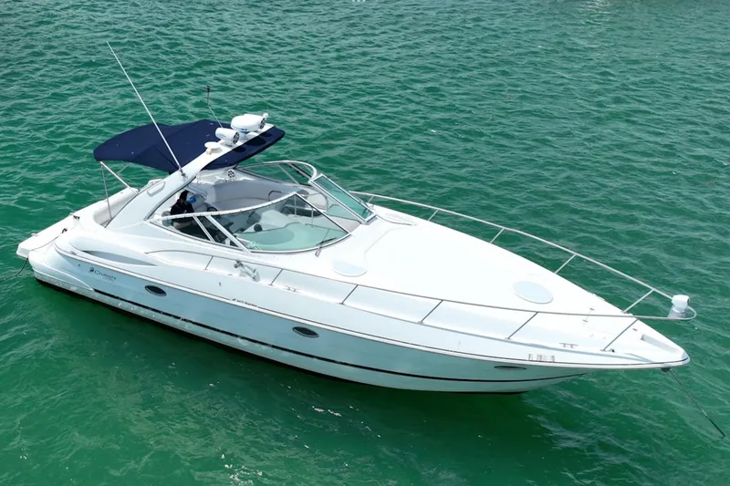 Slide: The Image of 2001 Cruisers Yachts 3470 Express boat on clear green water, featuring sleek design and blue canopy. - 3