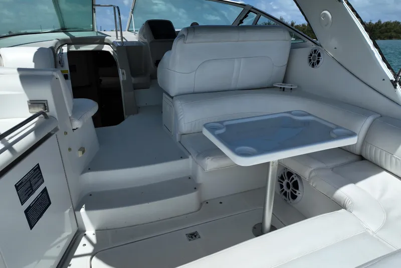 Slide: The Image of 2001 Cruisers Yachts 3470 Express interior with white seating and table, docked on water. - 5
