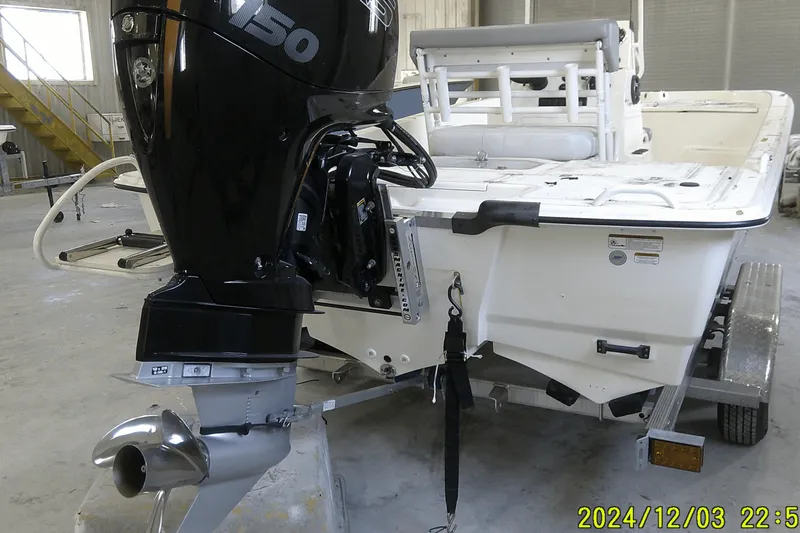 Slide: The Image of 2023 Mako Pro Skiff 19 CC boat with powerful outboard motor in a garage setting. - 2