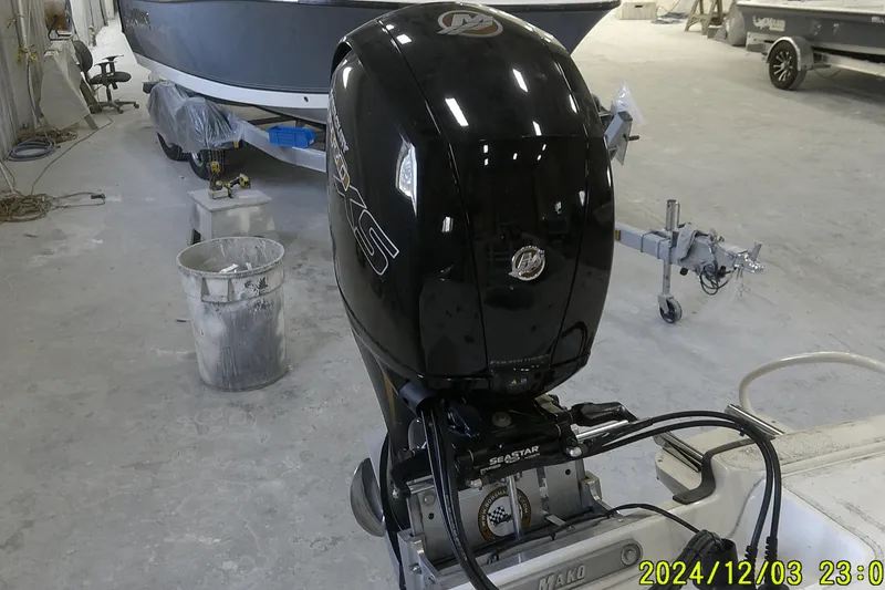 Slide: The Image of 2023 Mako Pro Skiff 19 CC boat with outboard motor in a workshop setting. - 45