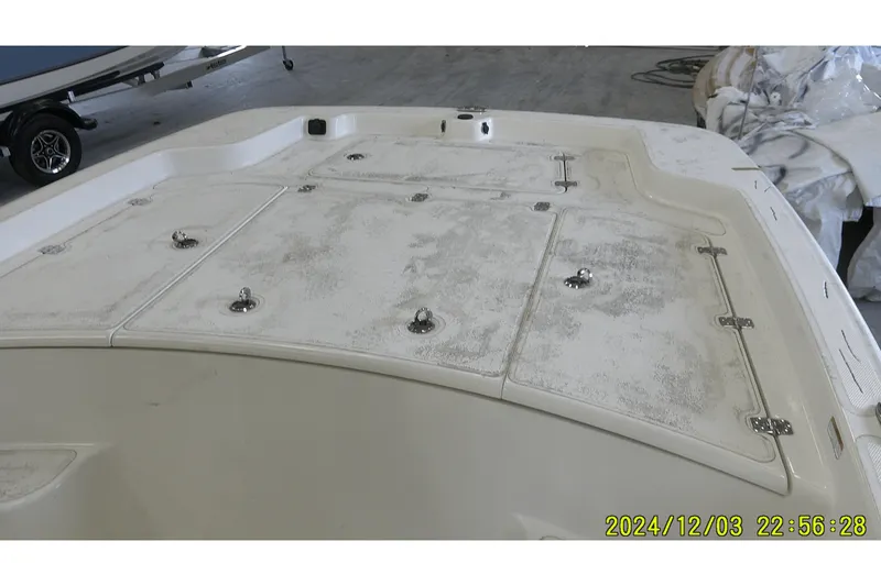 Slide: The Image of 2023 Mako Pro Skiff 19 CC boat deck with storage compartments in a garage setting. - 67