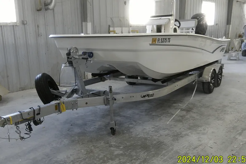 Slide: The Image of 2023 Mako Pro Skiff 19 CC boat on trailer in a garage setting. - 70