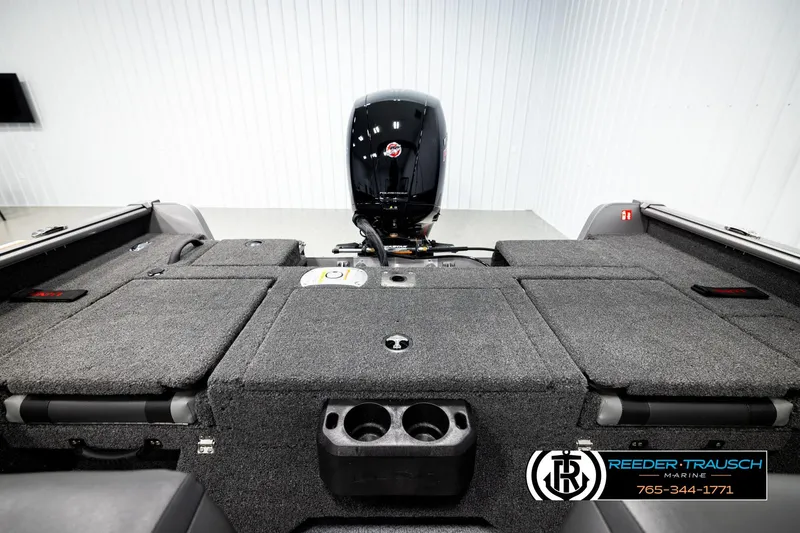 Slide: The Image of 2026 Lund 1875 Impact XS boat interior with motor, carpeted deck, and storage compartments. - 19