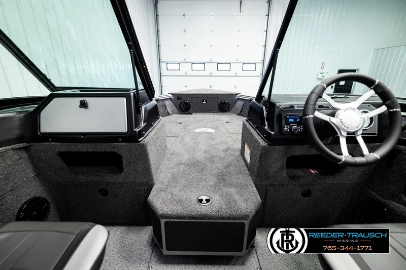 Slide: The Image of 2026 Lund 1875 Impact XS boat interior with steering wheel and dashboard in a showroom. - 28