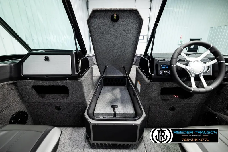 Slide: The Image of 2026 Lund 1875 Impact XS boat interior with open storage compartment and steering wheel. - 29