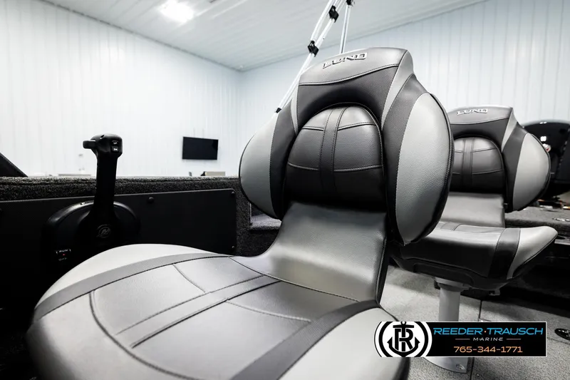 Slide: The Image of 2026 Lund 1875 Impact XS boat seats in a showroom, featuring sleek black and gray design. - 40