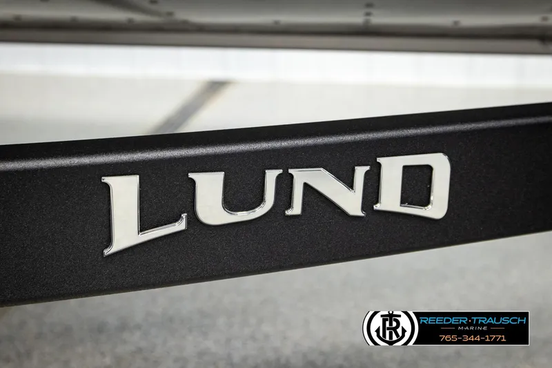 Slide: The Image of 2026 Lund 1875 Impact XS boat logo on a black surface, Reeder-Trausch Marine branding. - 54