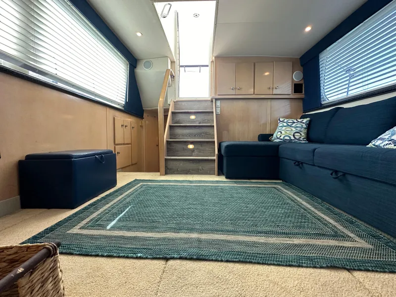 Slide: The Image of Interior of 2000 Carver 406 Motor Yacht with blue sofa, stairs, and large windows. - 21