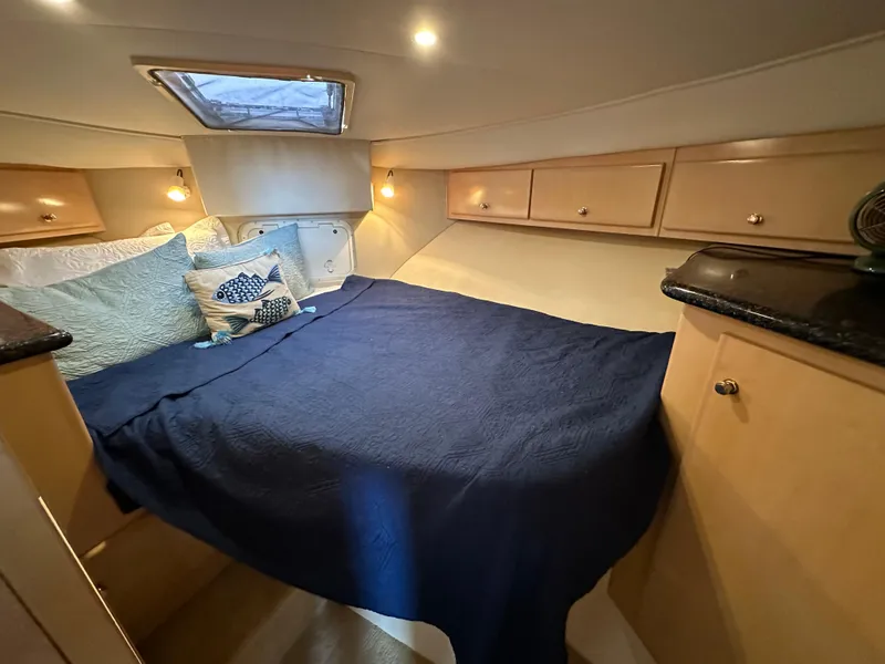 Slide: The Image of Cozy bedroom in a 2000 Carver 406 Motor Yacht with blue bedding and wooden cabinets. - 22