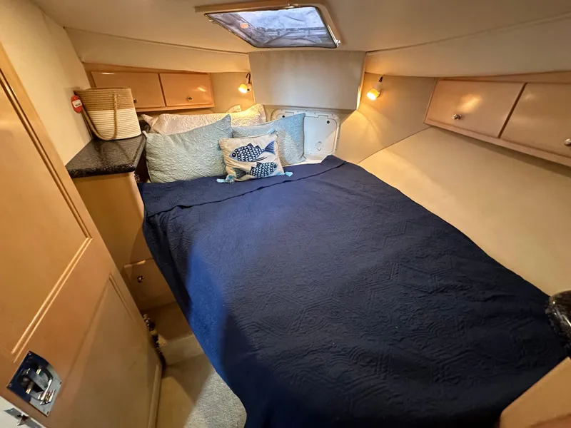 Slide: The Image of Cozy bedroom in a 2000 Carver 406 Motor Yacht with blue bedding and wooden cabinets. - 23