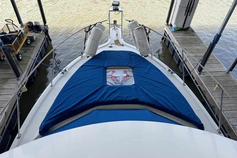 Slide: The Image of 1993 Carver 300 Aft Cabin boat docked, featuring blue cover and lifebuoy on deck. - 14
