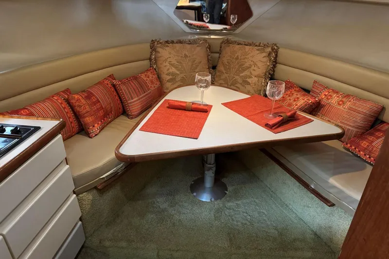 Slide: The Image of 1993 Carver 300 Aft Cabin interior with cozy dining area, red cushions, and elegant table setting. - 19