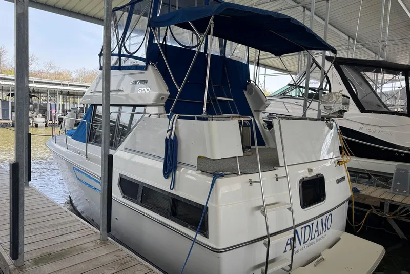 Slide: The Image of 1993 Carver 300 Aft Cabin boat docked, featuring blue canopy and white hull. - 7