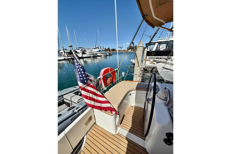 Slide: The Image of 2006 Beneteau Oceanis 523 sailboat docked, featuring American flag and marina view. - 21