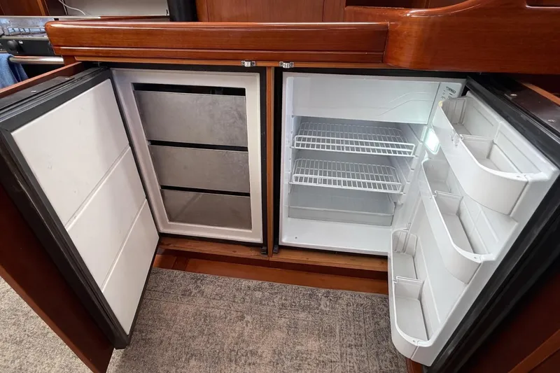 Slide: The Image of Interior view of a 2006 Beneteau Oceanis 523 yacht refrigerator, showcasing open fridge and freezer compartments. - 35