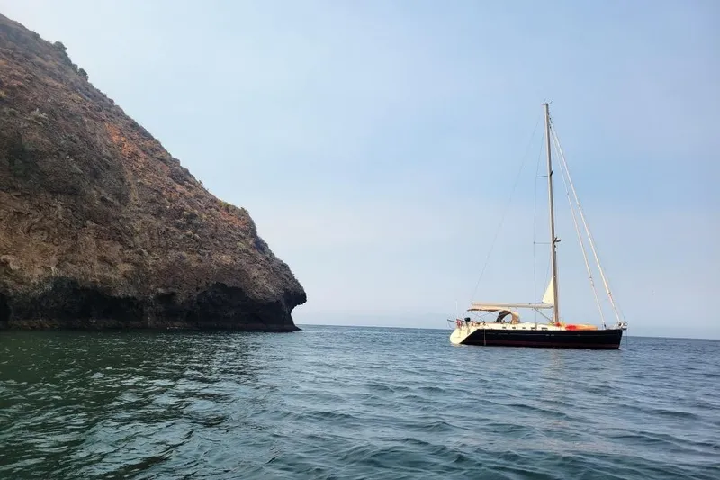 Slide: The Image of Sailboat Beneteau Oceanis 523 (2006) near rocky coastline on calm sea. - 75