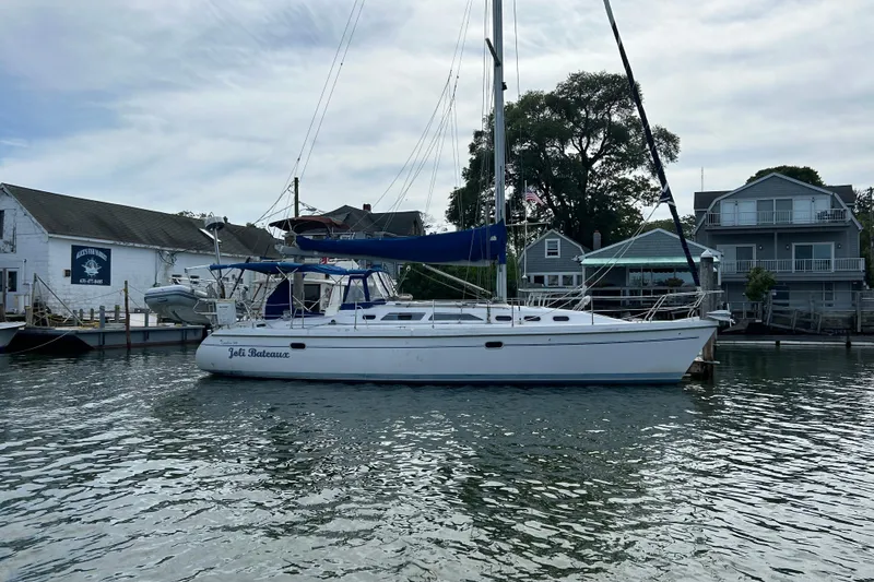 The Image of 2000 Catalina 380 sailboat docked at a marina with waterfront houses in the background. - 0