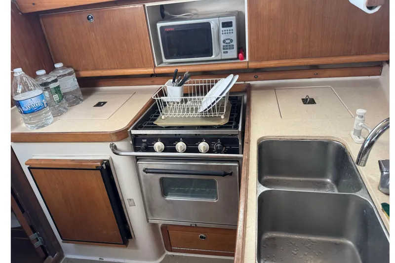 Slide: The Image of Compact kitchen in a 2000 Catalina 380 sailboat with stove, sink, and microwave. - 29