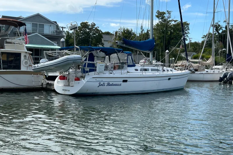 Slide: The Image of Catalina 380 sailboat from 2000 docked in a marina, featuring a dinghy and blue canopy. - 31