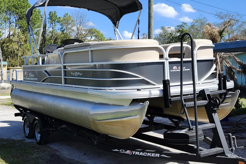 The Image of 2018 Sun Tracker Party Barge 20 DLX pontoon boat on trailer, parked outdoors. - 1