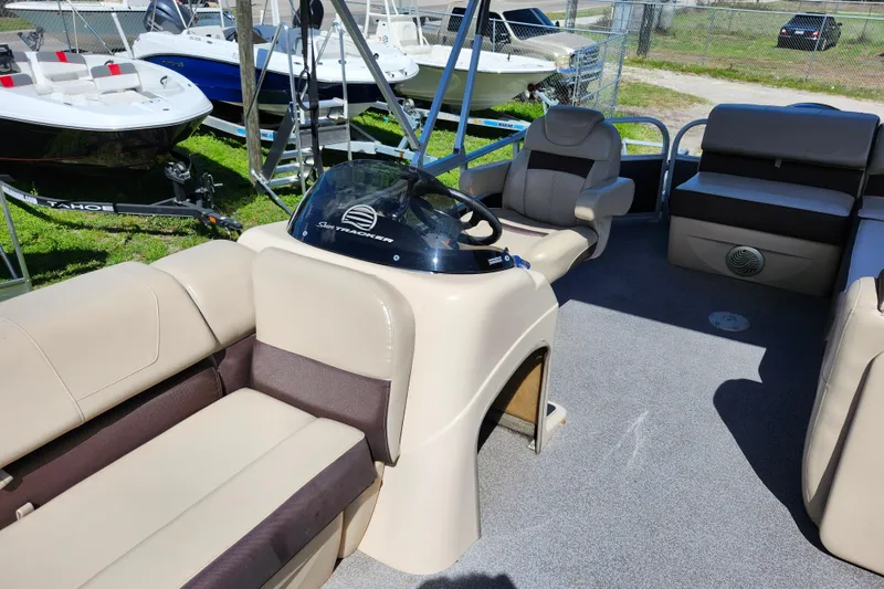 Slide: The Image of 2018 Sun Tracker Party Barge 20 DLX interior with beige seating and steering console. - 18