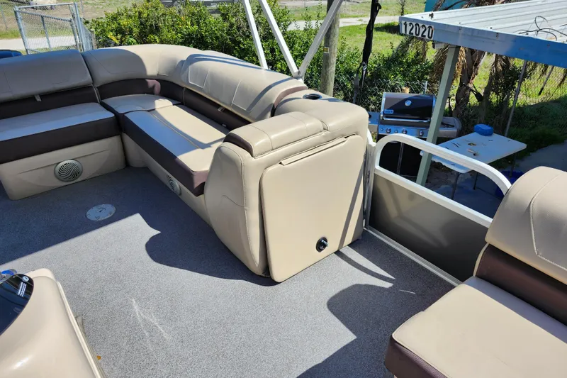 Slide: The Image of 2018 Sun Tracker Party Barge 20 DLX interior with beige seating and outdoor setting. - 19