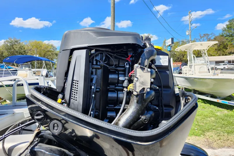 Slide: The Image of 2018 Sun Tracker Party Barge 20 DLX outboard motor, open for maintenance, under clear blue sky. - 8