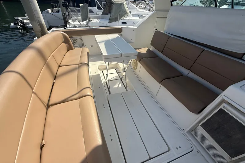 Slide: The Image of Spacious seating area on a 2000 Tiara Yachts 4000 Express, featuring tan cushions and a white table. - 16