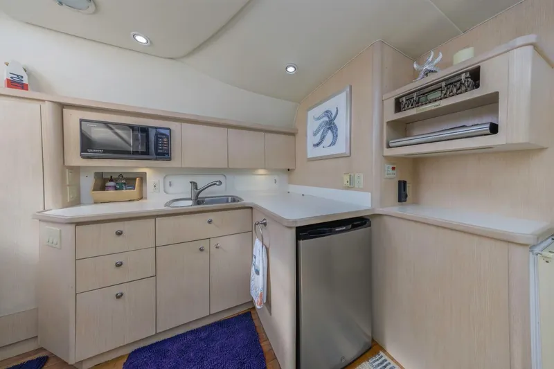 Slide: The Image of Modern kitchen in a 2000 Tiara Yachts 4000 Express, featuring light wood cabinetry and appliances. - 30