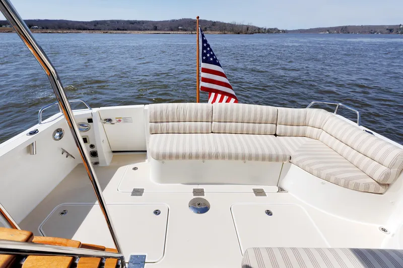 Slide: The Image of 2016 Sabre 42 Fly Bridge Sedan boat with striped seating and American flag on calm water. - 22