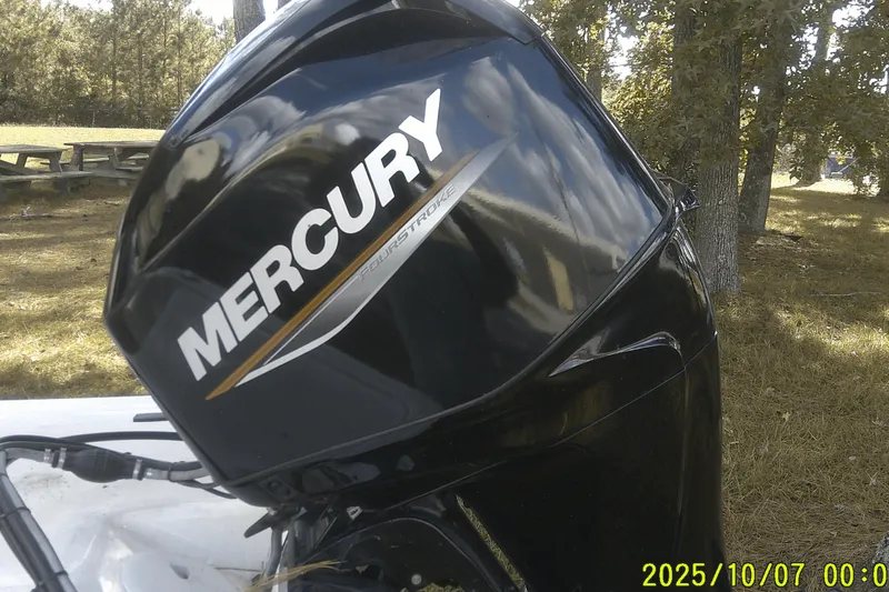 Slide: The Image of 2024 Mako Pro Skiff 15 CC with Mercury FourStroke engine in a wooded area. - 12