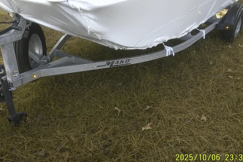 Slide: The Image of 2024 Mako Pro Skiff 15 CC boat on trailer, covered, parked on grass. - 2